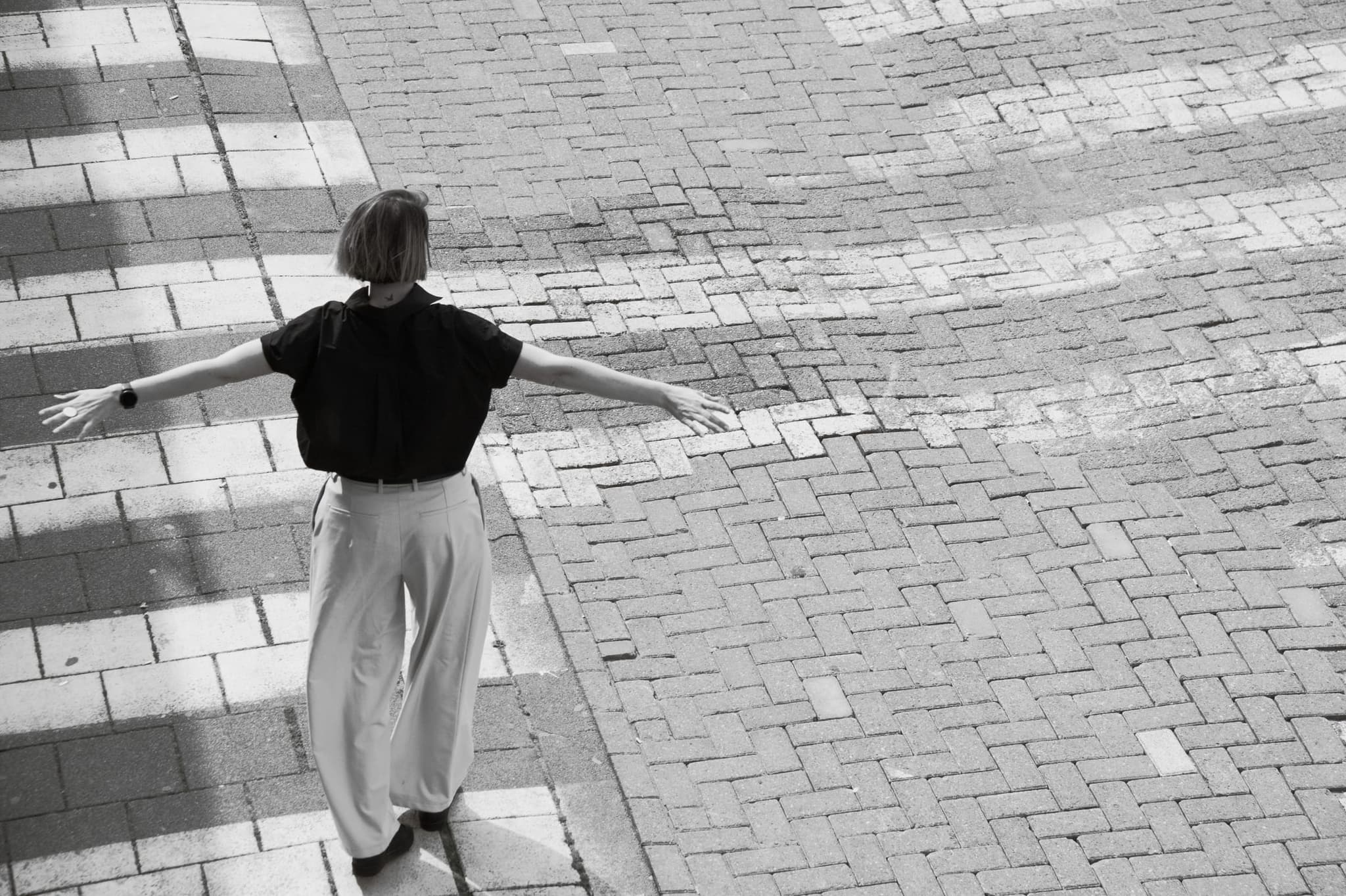Els loopt met gespreide armen over een zebrapad, van achteren gefotografeerd